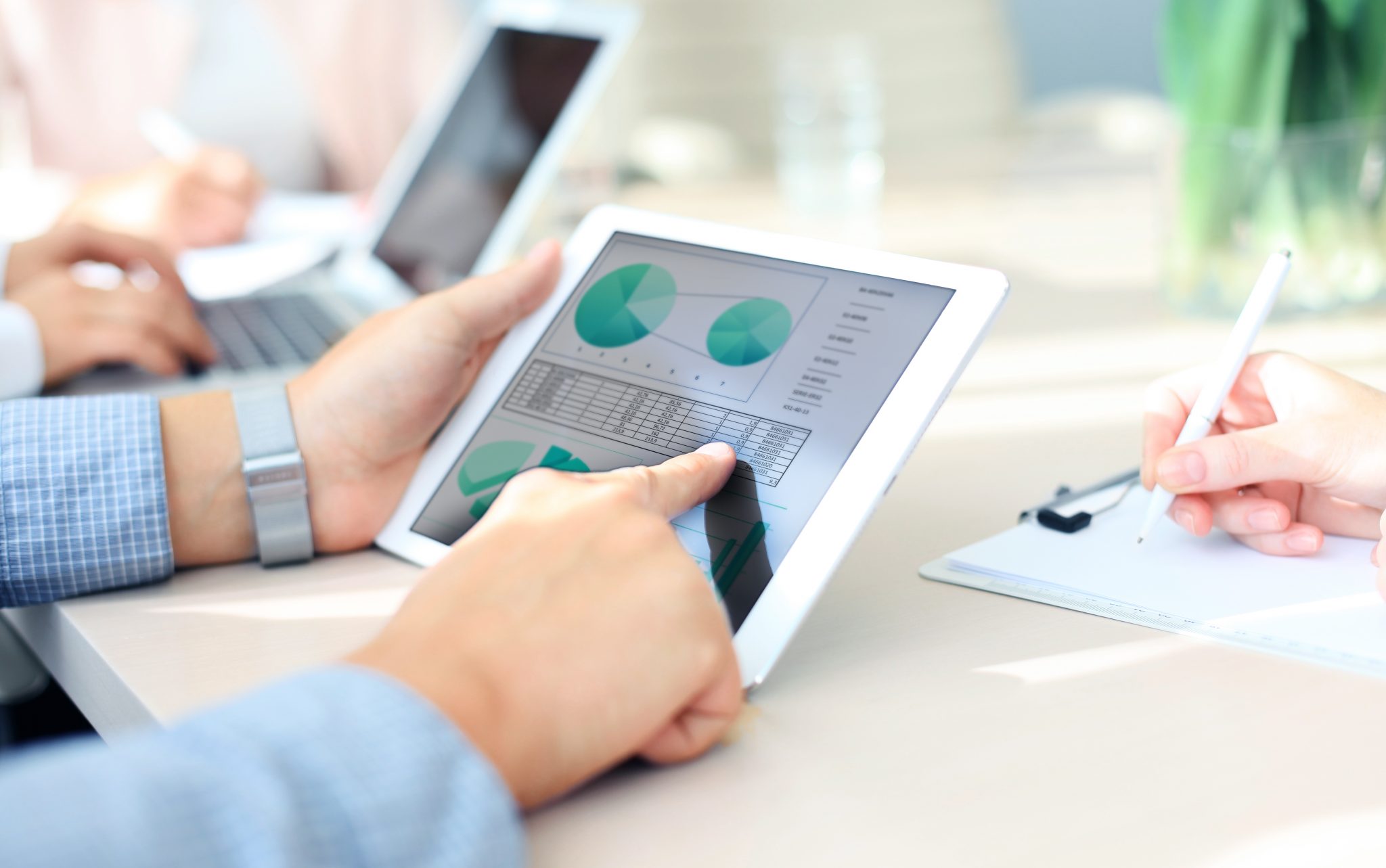 Business person analyzing financial statistics displayed on the tablet screen Modern Solutions